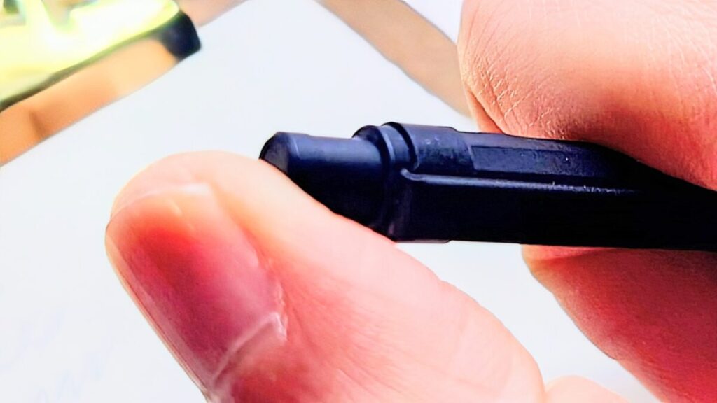 オレンズネロ0.3mmのノック部を親指で押す動作を捉えた写真。自動芯出し機構の起点となる瞬間。