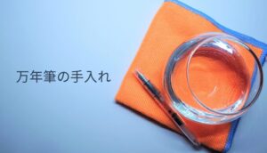 布巾の上に水を入れた容器と、洗浄前の万年筆が並べられている様子