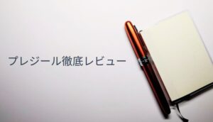 メモ帳のカバーに挿されたプラチナ万年筆プレジール。ノバオレンジのクリップが映える実用的な使用シーン