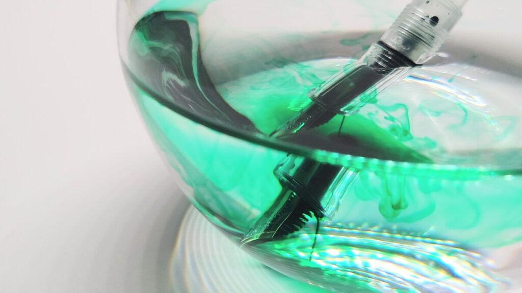 万年筆のペン先が水を入れた容器に浸けられている洗浄中の様子