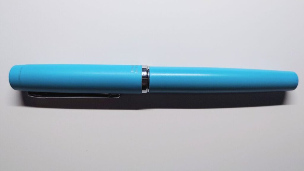 机の上に真横に置かれたプラチナ万年筆プロシオン。ターコイズブルーの質感が分かる