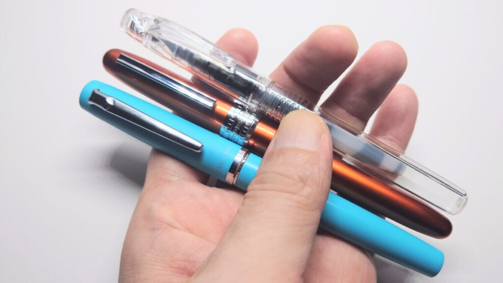 左手にプロシオン・プレジール・プレピーの3本の万年筆を持っている様子