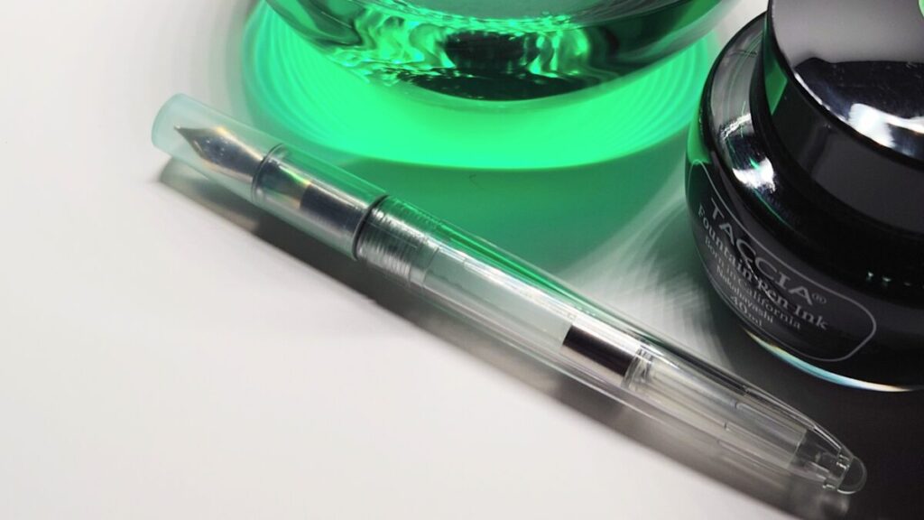 木製デスクの上に万年筆とインク瓶が並べられ、筆記具のある暮らしを感じさせる構図