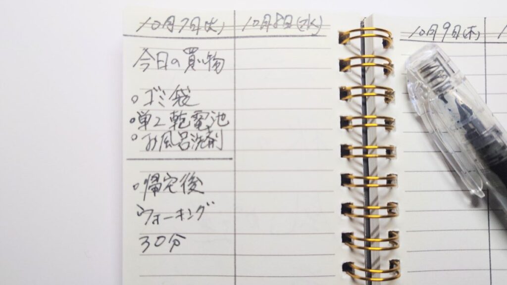 メモ帳に万年筆で書かれた文字と、その横に置かれた万年筆本体