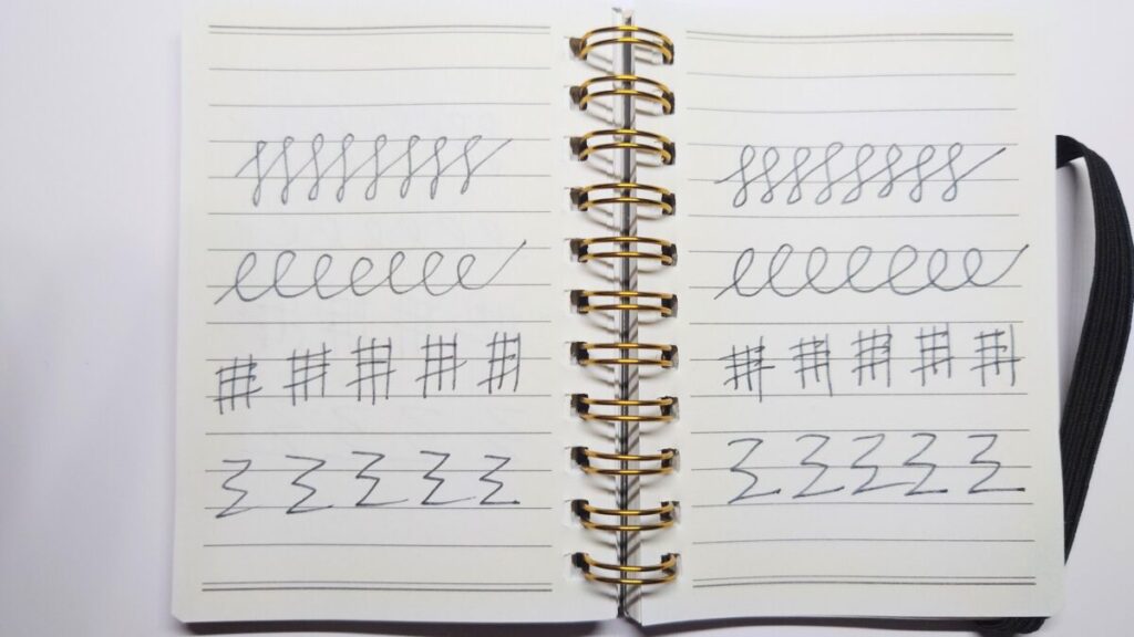 見開きメモ帳に、万年筆で書いた線の比較画像。左ページは60度の筆記角度で細めの線、右ページは45度の角度で太めの線が描かれており、筆記角度による線の違いが視覚的にわかる構成。